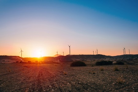 Wind farm turbines silhouette at sunset behind the field in Cyprus. Renewable energyの写真素材