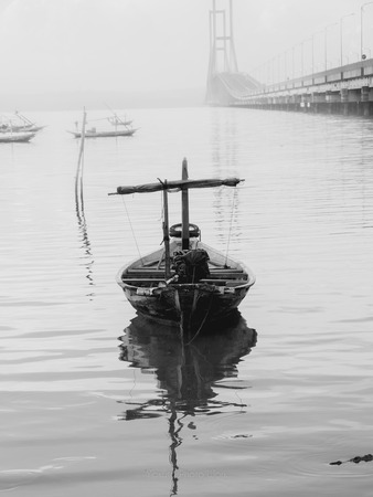 Dramatic Empty Fishing Boat beside a bridgeの写真素材