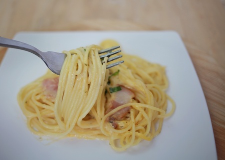 spaghetti carbonara with cream on white plate, closeup, macro, top view, abstract, texture, on wooden backgroundの写真素材