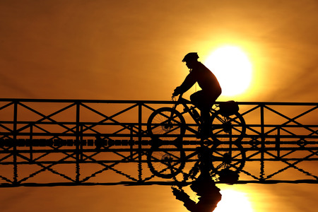 silhouette of a cyclist at sunsetの写真素材