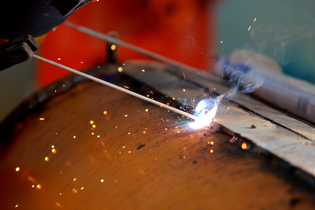 Close-up worker with protective mask welding metal.