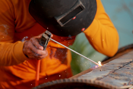 Close-up worker with protective mask welding metal.
