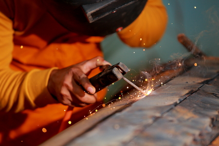 Close-up worker with protective mask welding metal.