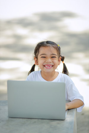 Little kid girl asian uses a laptop to learn at school. The child smiles happily and gets knowledge...