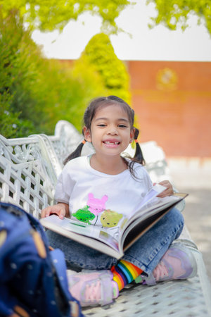 Little kid girl asian reading a book after classes learning homework with intention which increases...