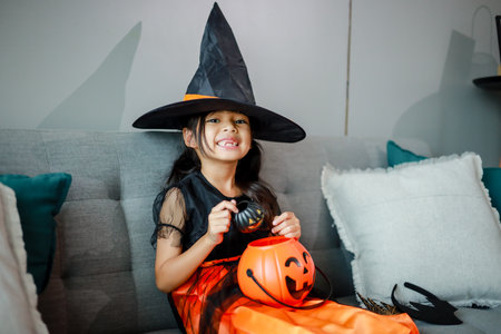 Halloween, holiday and childhood concept. Little kids southeast asian on halloween dressed in a witch costume.の写真素材