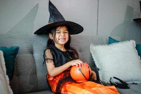 Halloween, holiday and childhood concept. Little kids southeast asian on halloween dressed in a witch costume.の写真素材