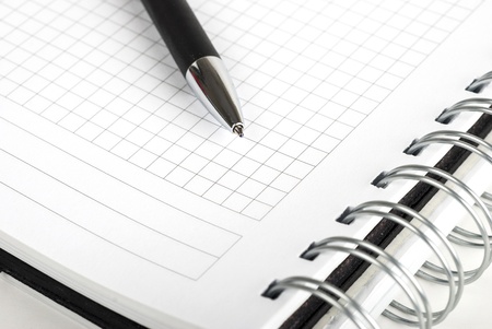 Pen and spiral notebook on white background