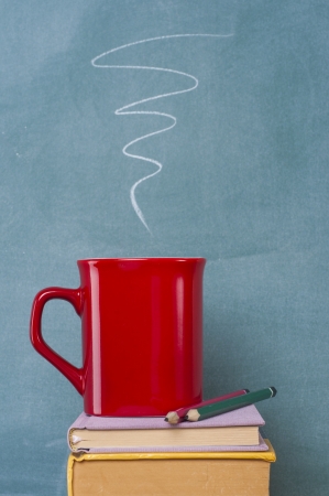 books coffee mug and pencil in front of green chalkboardの写真素材
