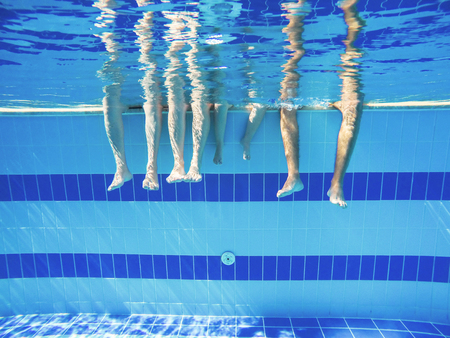 feet of people moving under the water in the poolの写真素材