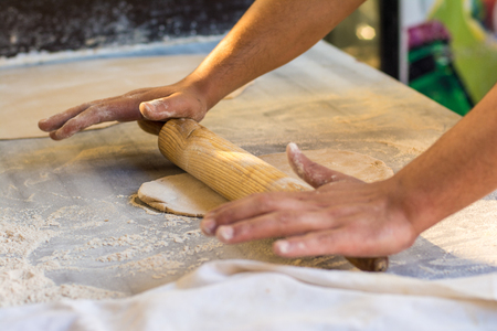 Chef Rolling dough with wooden roller and flourの写真素材