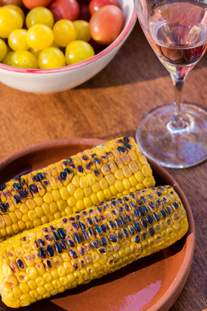 Grilled corn served with wine and fresh tomatoの写真素材
