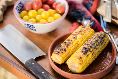 Grilled corn served with wine and fresh tomatoの写真素材