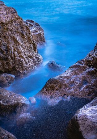Long exposure image of Dramatic sky seascape with rock in sunset scenery backgroundの写真素材
