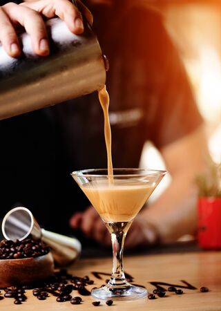 Barmen pouring coffee cocktail on wooden barの写真素材
