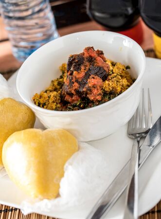 Regional African Food on white plate on wooden backgroundの写真素材