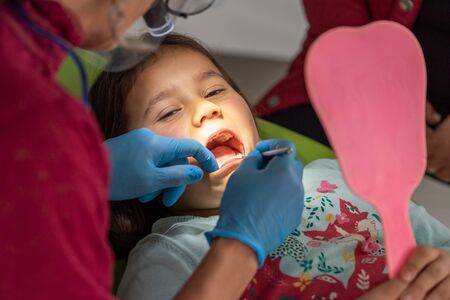 Dentist examining young girl in dental clinic