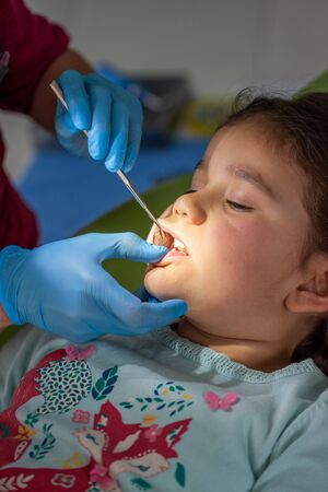 Dentist examining young girl in dental clinic