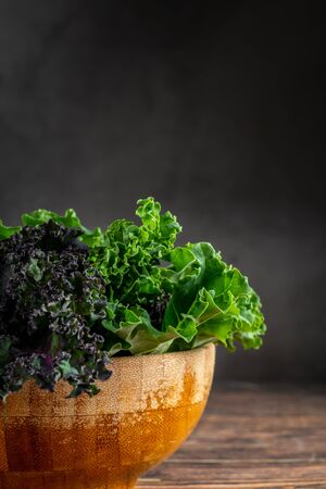 green leafy kale vegetable in bamboo bowl on wooden table backgroundの写真素材
