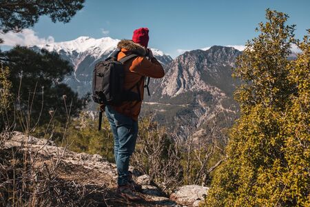 Young Caucasian male photographer on top of a mountain on clear day.