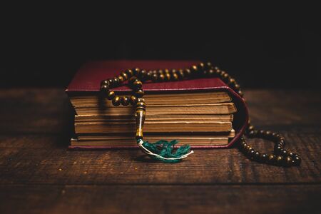 Holy Al Quran and prayer beads on wooden table. Ramadan muslim religion concept.