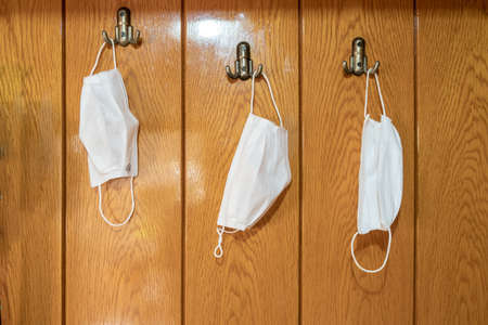 Covid-19 fabric face masks hanging at home door hooks.の写真素材
