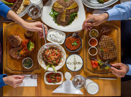 beautifully served table with different restaurant dishes and handsの写真素材