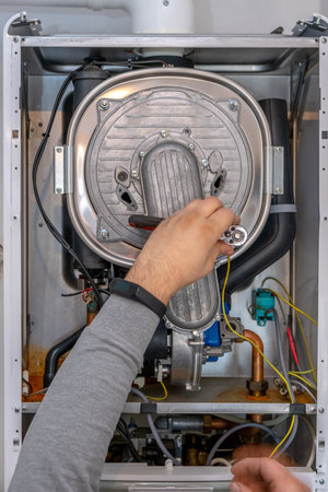 plumber repairing a condensing boiler in the boiler room.の写真素材