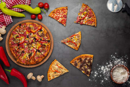Pizza slices with tuna, salami, mushrooms, pepperoni and spices on black background, copy space, top...