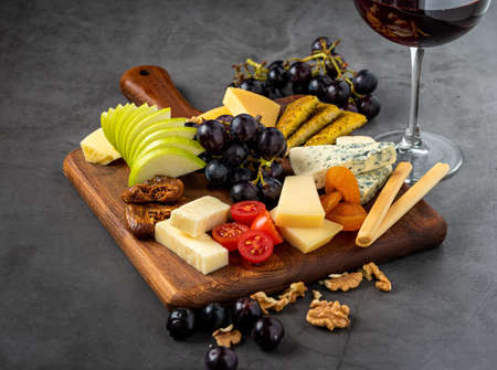Red Wine And Assorted Cheese Plate with fruit on wooden plate