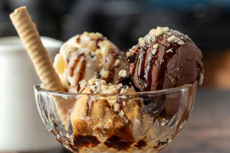 Chocolate, cream and caramel Roma ice cream in a glass bowl with hazelnut and chocolate sauce poured...