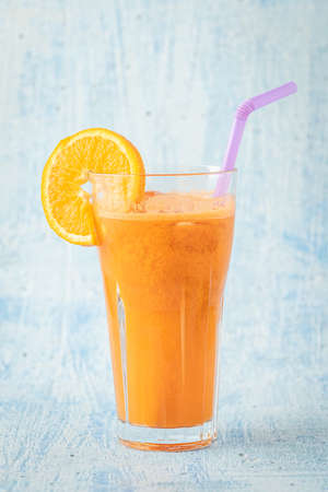 carrot and orange fresh juice on blue tableの写真素材