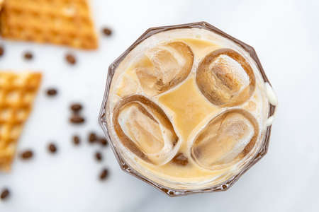 Iced caramel latte coffee in a tall glass with caramel syrup