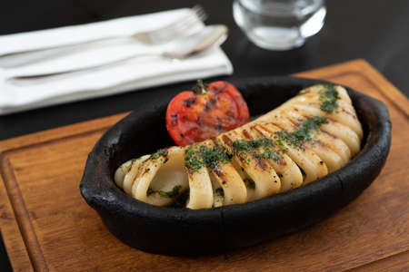 Grilled squid with tomatoes on a clay plate. selective focus.の写真素材