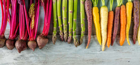 Various root vegetables on wooden background. Radishes, colorful carrots and asparagus.の写真素材