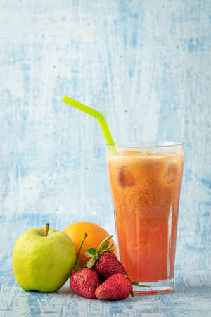 Energizing and refreshing apple, strawberry and orange mix juice on blue stone backgroundの写真素材