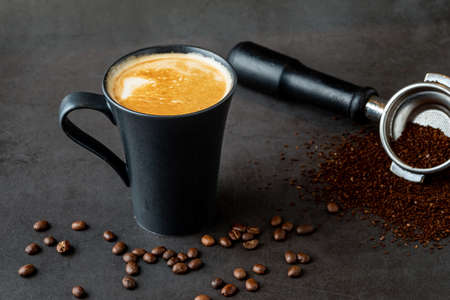 Relaxing latte coffee in black porcelain cup on stone table