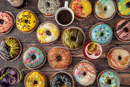 Top view of donuts in various colors and flavors on wooden tableの写真素材