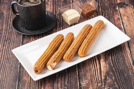 Hot churros with chocolate sauce on wooden tableの写真素材