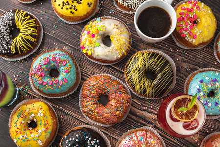 Top view of donuts in various colors and flavors on wooden tableの写真素材
