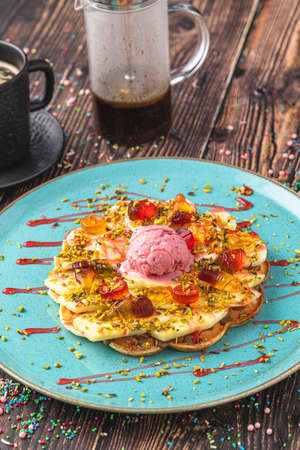 Heart waffle with banana and strawberry with gummy candy and ice cream on it.の写真素材