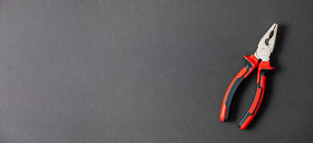 Pliers in red and black colored on a black background with blank text space