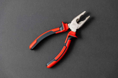 Pliers in red and black colored on a black background with blank text spaceの写真素材