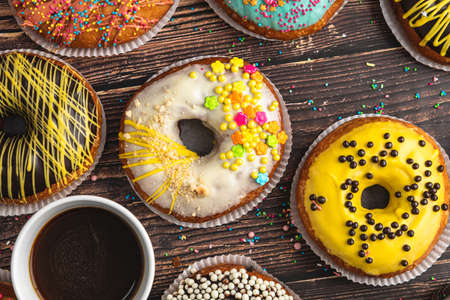 Top view of donuts in various colors and flavors on wooden tableの写真素材