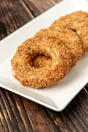 Turkish name Kandil simidi with tea beside it on wooden table. Turkish Bagel with sesame seeds or...
