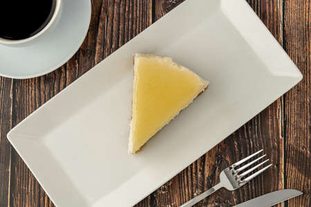 Delicious lemon cheesecake served with coffee on wooden table