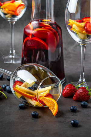 Glass of red Sangria and fruits on dark stone table