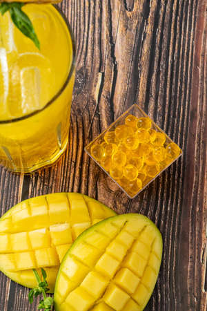 Mango lemonade with bubble tea on dark wooden background