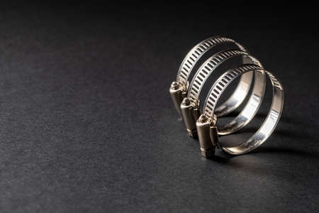Metal hose clamp on black background. Empty space for text