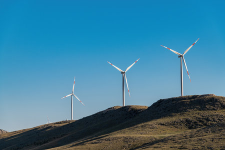 clean electricity producing wind turbine or windmill built on a windy mountain ridgeの写真素材